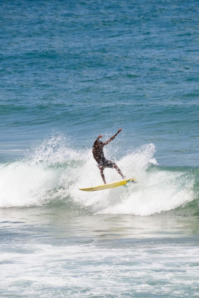 Ein Mann steht auf einem Surfbrett und reitet eine Welle im Wasser.