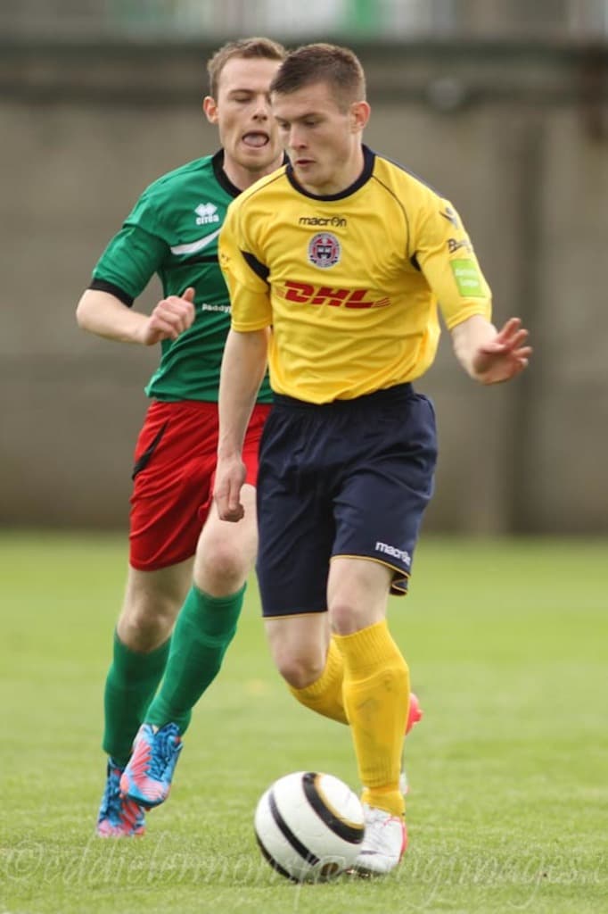 Zwei Männer spielen ein Fußballspiel auf einem grünen Feld mit einem Ball, mit einem unscharfen Hintergrund und Text unten.