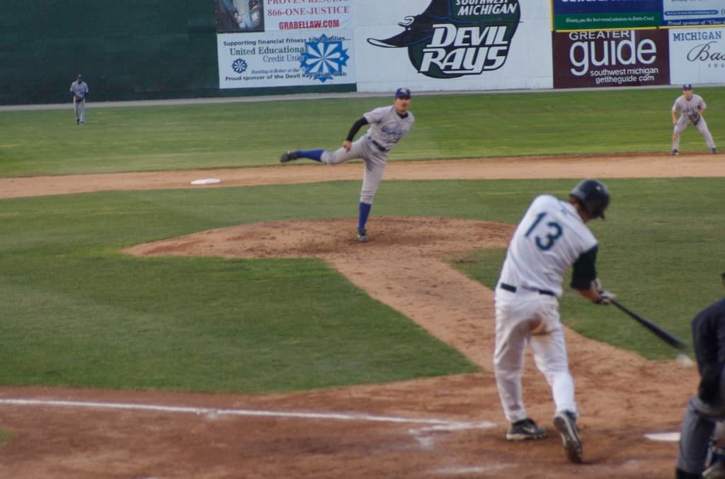 Eine Gruppe von Menschen spielt Baseball auf einem Feld mit Bannern im Hintergrund.