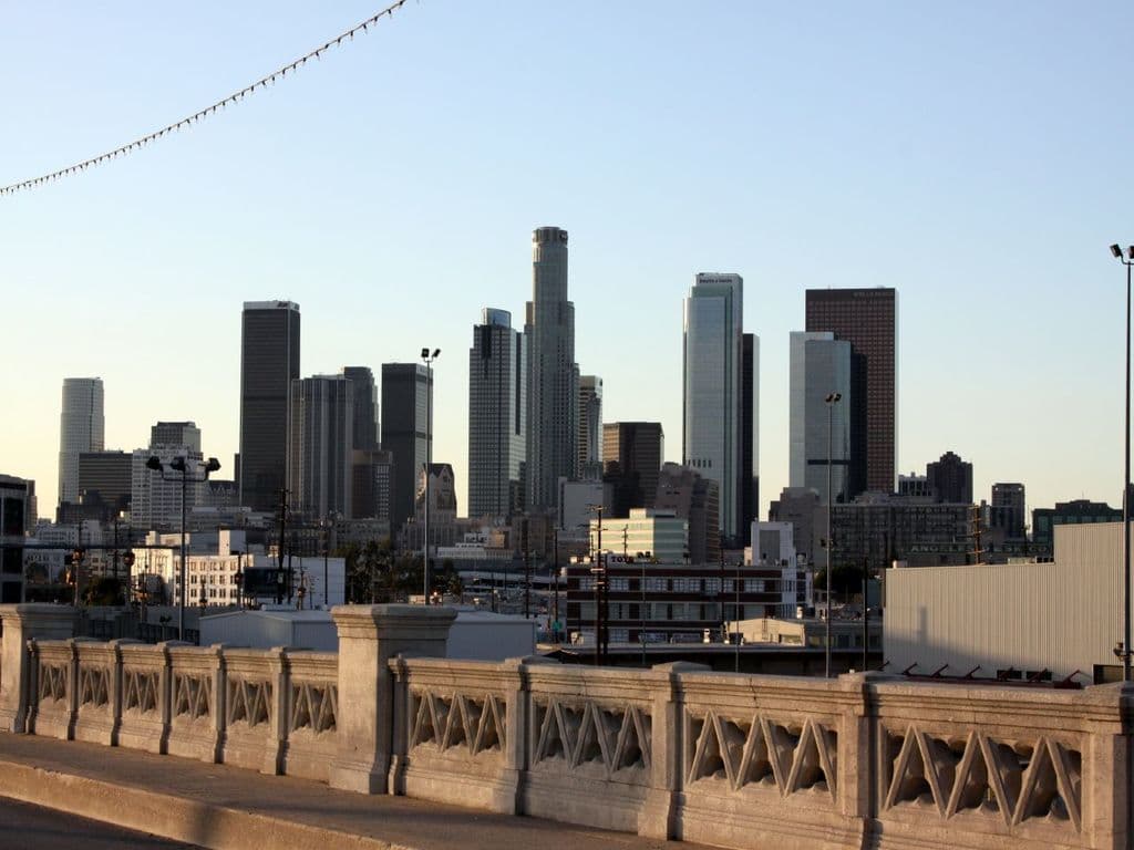 Ein Geländer im Vordergrund mit hohen Gebäuden und Pfählen im Hintergrund.