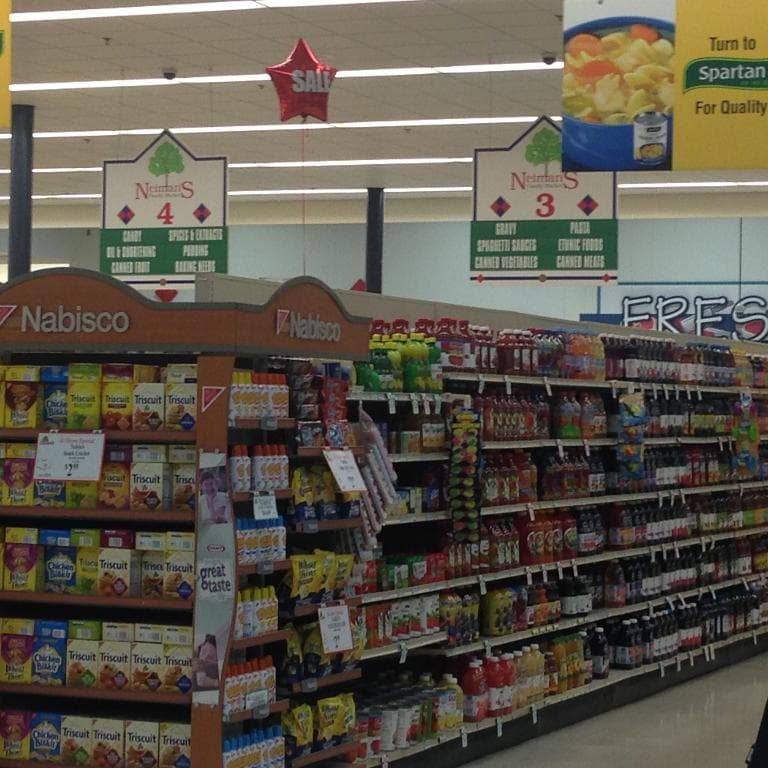 Ein Supermarktinneres mit sichtbaren Lebensmitteln, Deckenleuchten und Schildern.