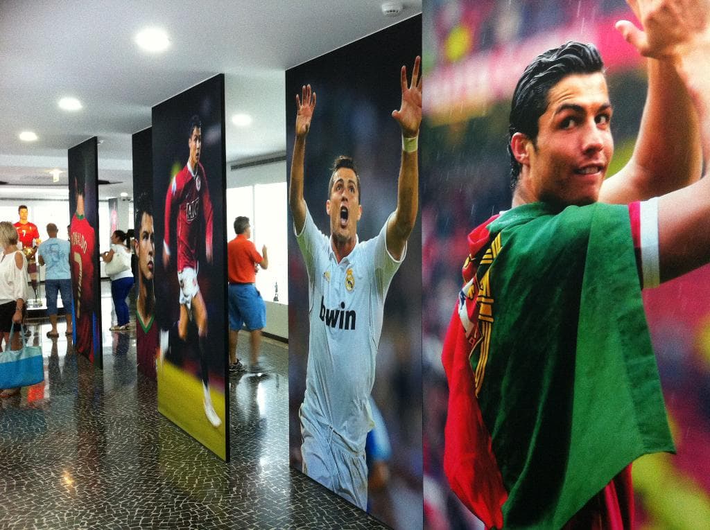 Ein Banner mit einem berühmten Fußballspieler namens Rolando, mit Menschen, die links neben einem Tisch stehen und Lichter oben.