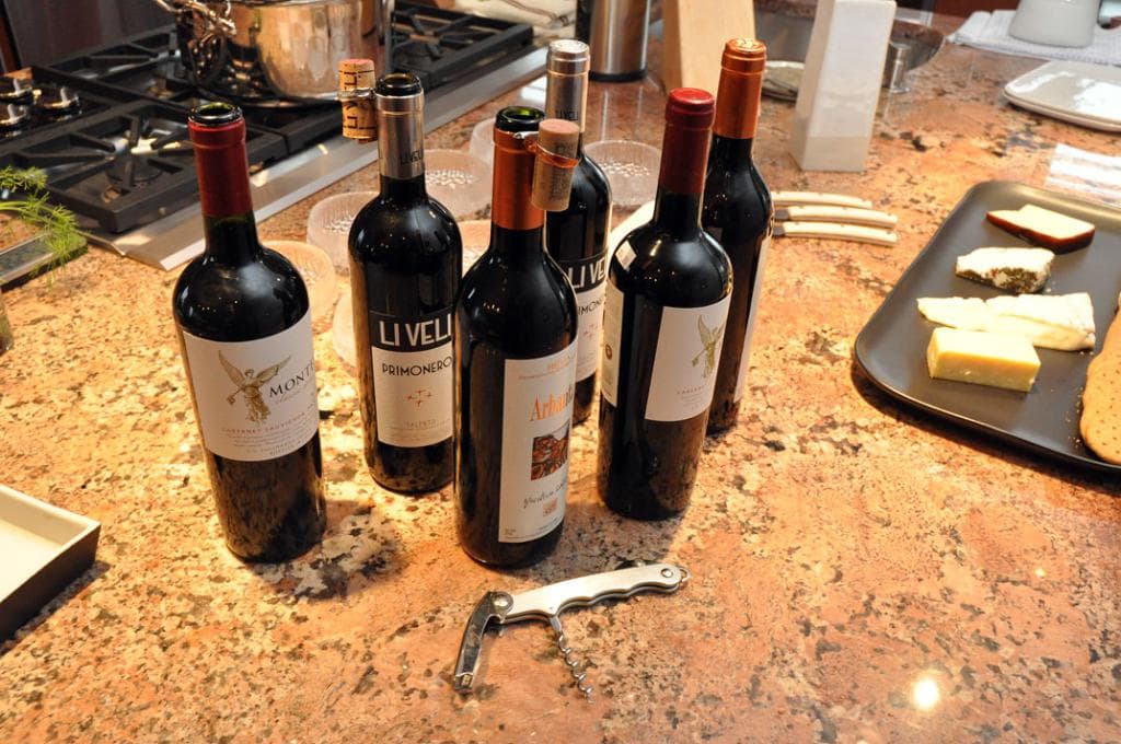 Eine Küchenplattform mit einem Topf auf dem Herd, Flaschen, ein Tablett mit Lebensmitteln, Messer, Schüsseln, eine Nagelschere und andere Gegenstände.