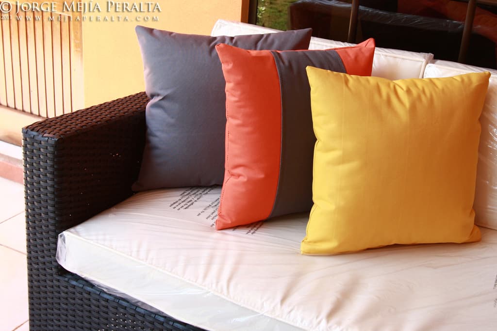 Ein Sofa mit Kissen vor einem Glasfenster und einer Wand, mit Text oben im Bild.