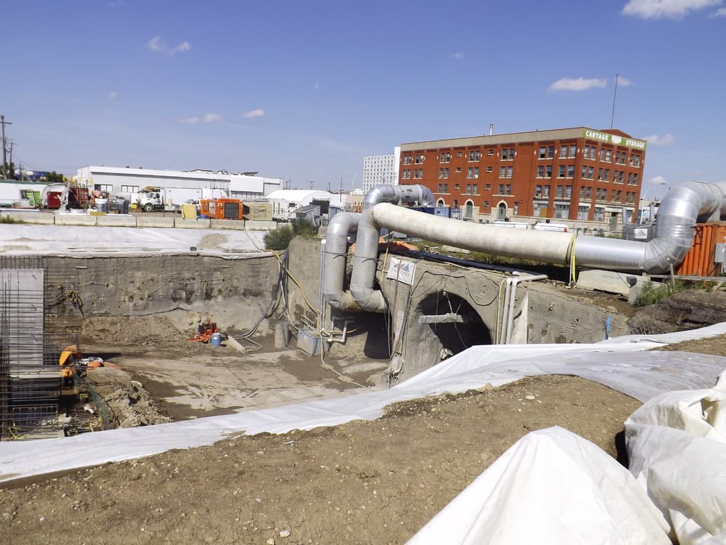 Eine Szene mit Gebäuden, einem Zaun, Fahrzeugen, aktuellen Umfragen, einer Leitung und dem Himmel darüber.