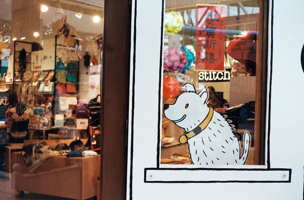 Eine Illustration eines Hundes mit Text auf der rechten Seite und auf der linken Seite ein Raum mit Lampen, Flaggen, Regalen, Sofas, Kleidung, Dekorationen, Menschen, Stühlen und verschiedenen anderen Gegenständen.