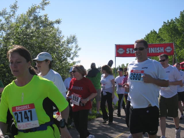 Eine Gruppe von Kindern läuft bei einem Marathon mit einem roten Banner und Bäumen im Hintergrund.