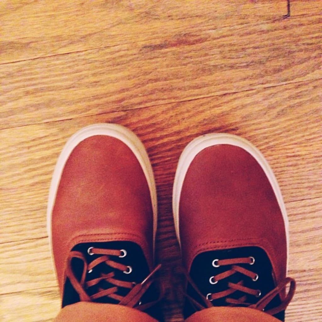 Schuhe in Braun und Schwarz auf einer braunen Oberfläche.