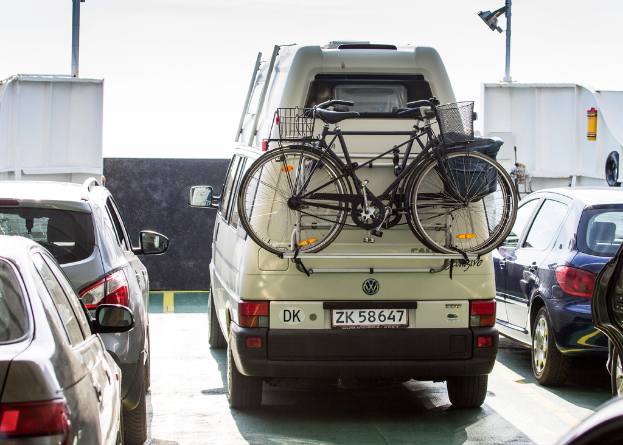 Verschiedene Fahrzeuge, darunter Autos und Fahrräder in verschiedenen Farben, sind in der Mitte des Bildes positioniert.