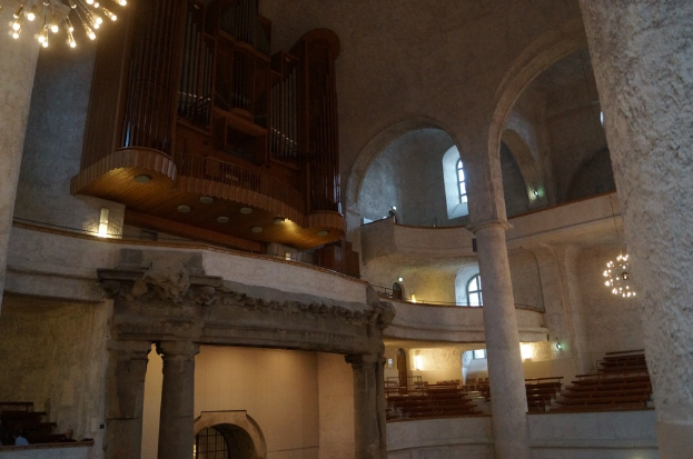 Der Innenraum eines Gebäudes mit Lampen, Treppen, Säulen, einem hölzernen Objekt an der Wand, Fenstern und Türen.