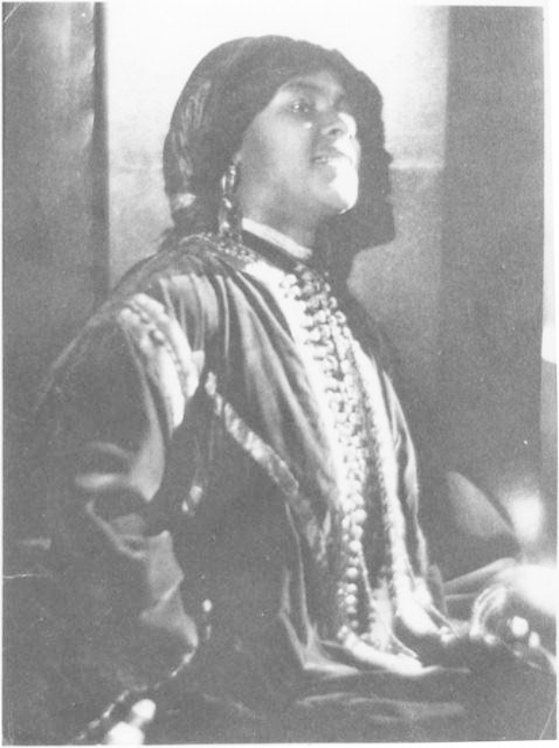 Schwarz-weiß-Fotografie einer Frau in Kleidung und Schmuck vor einer Wand sitzend, mit Text unten, der sie als erste indische Frau identifiziert, die zum US-Präsidenten gewählt wurde.