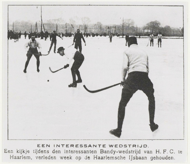 Ein Schwarz-Weiß-Foto einer Gruppe von Männern, die Hockey auf einem Eisplatz spielen, umgeben von Bäumen und Pfosten, mit Text unten.