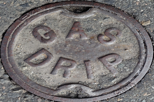 Ein Metall-Schachtobel auf dem Boden mit der Inschrift "Gas Tropfen".