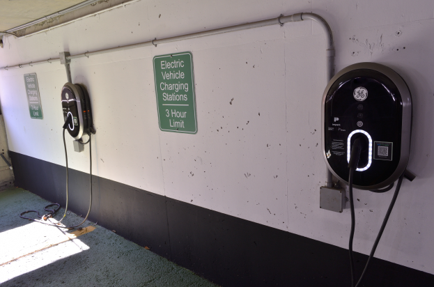 Eine Ladesäule für Elektrofahrzeuge in einer Tiefgarage mit zwei an der Wand angebrachten Ladesäulen und Tafeln mit Text, der Boden ist unten im Bild zu sehen.