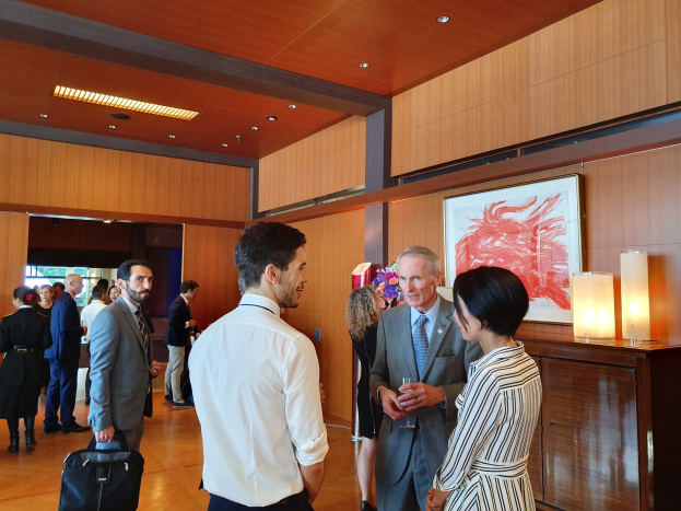 Menschen, die in einem Raum mit Holzw├Ąnden stehen und sich unterhalten, mit einem Foto Rahmen und Beleuchtung, einige halten Taschen bei einer Kunstmesse im Nationalmuseum Singapur.