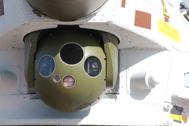 Nahaufnahme eines Militärfahrzeugs mit einer runden, grün-weißen Rakete, die seitlich in einem Metallrahmen montiert ist.