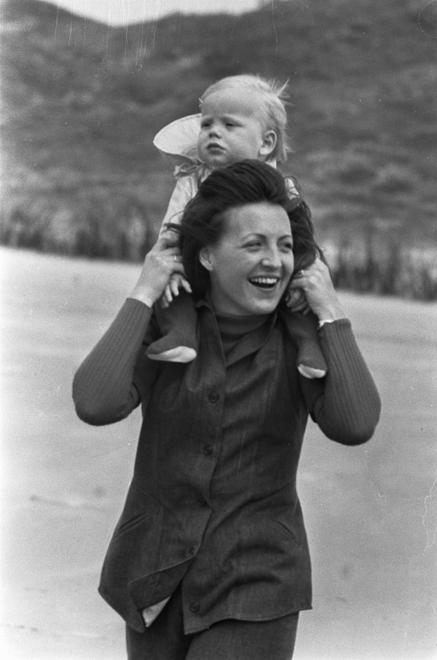 Eine Frau, die glücklich ist und ein Baby hält, mit einem sanft unscharfen Hintergrund, der einen träumerischen Effekt erzeugt.