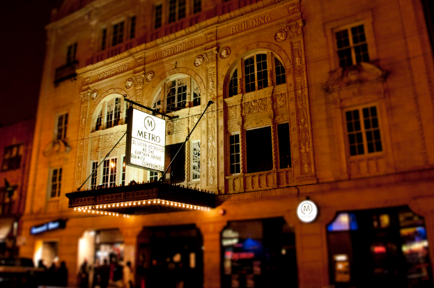 Ein gelbes Gebäude mit Geschäften im Erdgeschoss, von denen eines ein weißes Schild mit dem Wort "Metro" darauf hat.