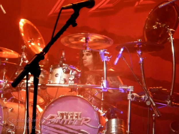 Eine Musikband spielt mit einem Musiker, der von konzentriertem rotem Licht umgeben ist.