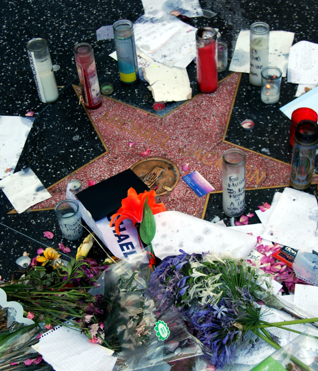 Star auf dem Hollywood Walk of Fame umgeben von Blumenbouquets, Kerzen, Papieren und anderen Gedenkobjekten.