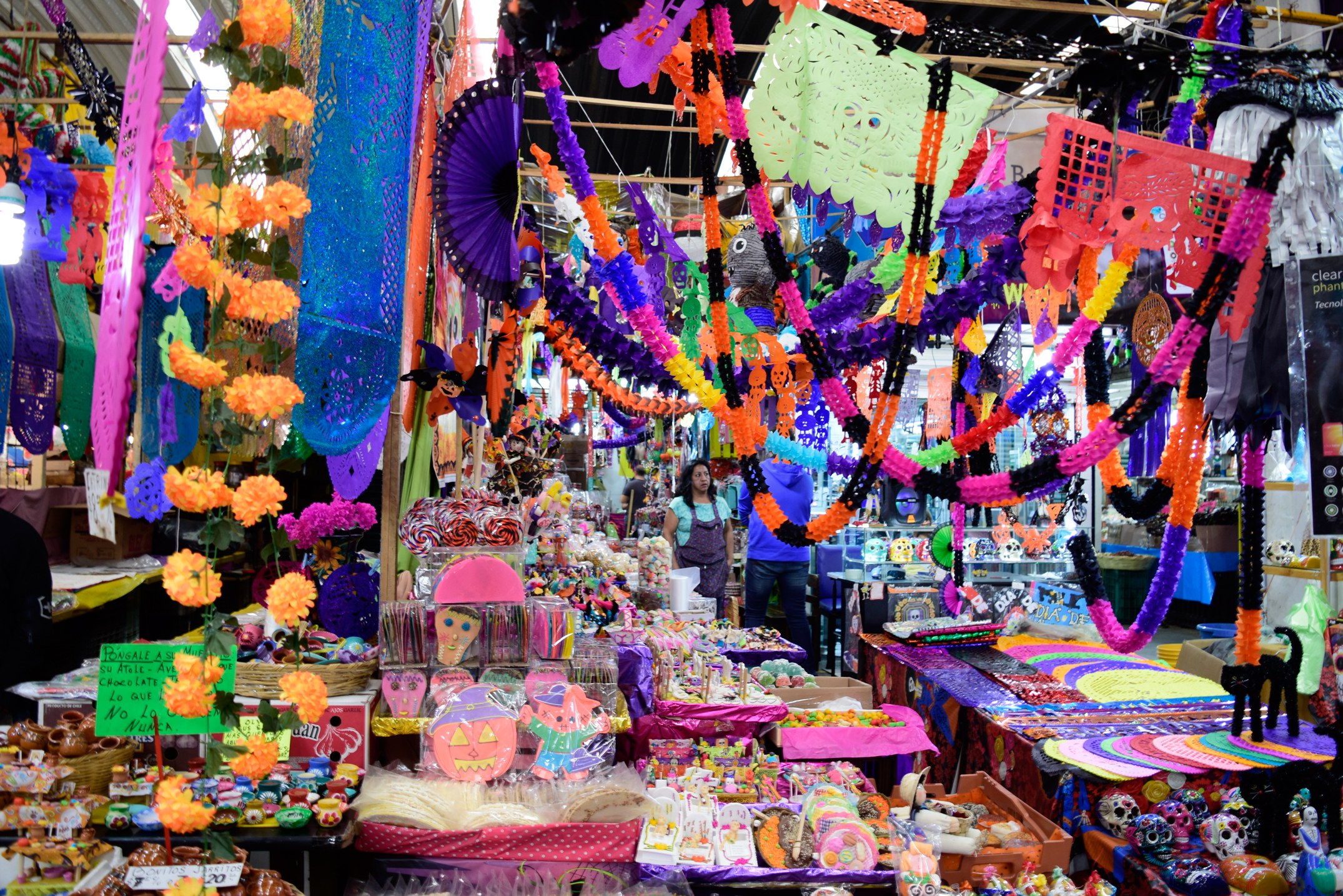 Ein belebter Markt mit Ständen, die Spielzeug, Dekorationsartikel und andere Gegenstände verkaufen, unter Deckenbeleuchtung mit Menschen, die durchschlendern.