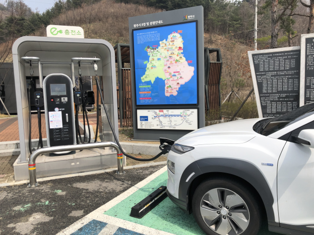 Elektrisches Auto an einer Station umgeben von Bäumen in Seoul, Südkorea, mit Himmel im Hintergrund.