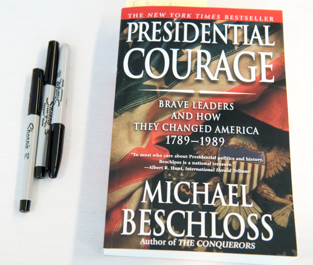Eine weiße Oberfläche mit einem Buch namens 'Präsidiale Courage: Mutige Führer und wie sie Amerika 1789-1989 veränderten' von Michael Beschloss, begleitet von zwei Stiften.