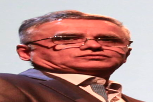 Ein Mann im Blazer, Krawatte und Brille steht vor einem weißen Hintergrund, identifiziert als CEO der Bank of England.