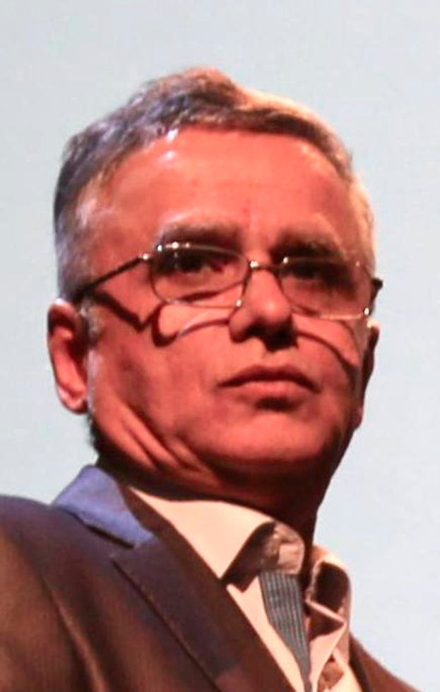 Ein Mann im Blazer, Krawatte und Brille steht vor einem weißen Hintergrund, identifiziert als CEO der Bank of England.