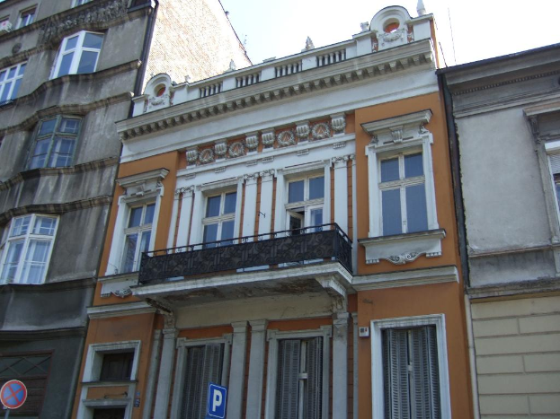 Gebäude mit Türen und Fenstern, Absperrtafeln an Pfählen, unter einem klaren Himmel.