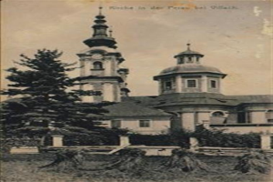 Ein altes Schwarz-Weiß-Foto einer Kirche mit einem Glockenturm, umgeben von Bäumen und Gras, mit einem klaren Himmel im Hintergrund. Der Text "München in der Prässel-holz" ist oben auf dem Bild zu sehen.