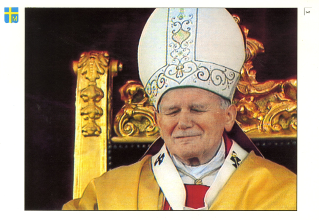 Ein Mann in priesterlicher Gewandung und einem weißen Hut sitzt auf einem Stuhl vor einem dunklen Hintergrund und sieht königlich und würdevoll aus.