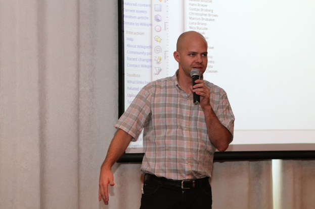 Eine Person steht mit einem Mikrofon vor einem Projektionsschirm.