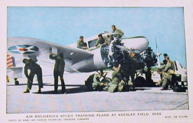 Gruppe von Menschen um ein Trainingsflugzeug auf einer Landebahn mit einem klaren blauen Himmel im Hintergrund, Text unten lautet "Luftmechanikerstudium Trainingsebene auf Keesler Field, Miss."