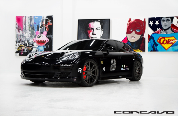 Ein schwarzer Nissan-Sportwagen ist vor Cartoon-Postern geparkt, mit einer kleinen Inschrift am unteren Bildrand.