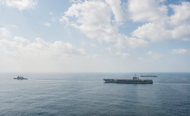 Drei Schiffe segeln auf einem Gewässer unter einem bewölkten Himmel.