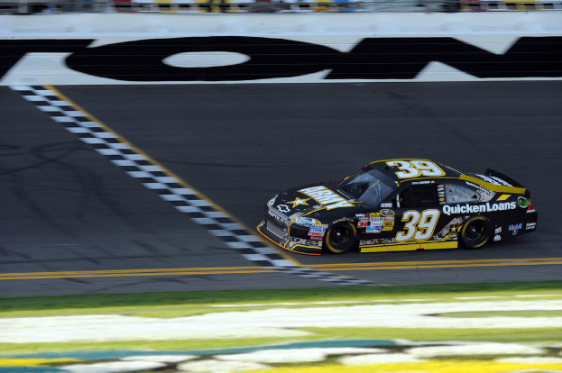 Ein Rennwagen auf einer Straße mit Gras am Boden, mit Text auf der Karosserie.