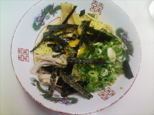 Ein weißer Teller auf einem Tisch mit einem Gemüse-Salat, Nudeln und Mehlstangen.