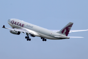 Ein Airbus A330-300 der Qatar Airways mit weißer und maronfarbener Lackierung, der durch einen blauen Himmel fliegt, die Flügel weit ausgebreitet.