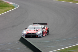 Nissan GT-R Nismo GT3 Rennauto auf der Nürburgring 24 Stunden Strecke, flankiert von grünem Gras.