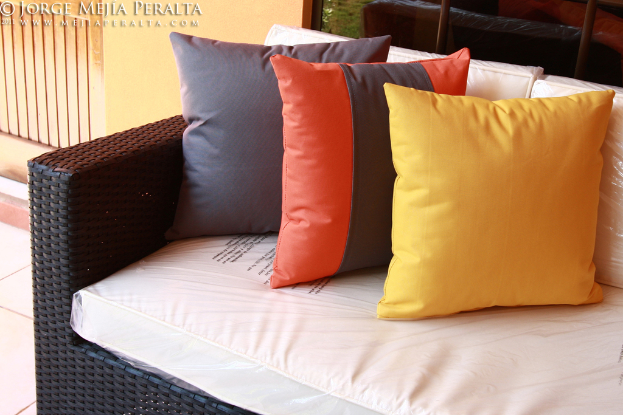 Ein Sofa mit Kissen vor einem Glasfenster und einer Wand, mit Text oben im Bild.