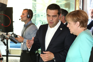 Bundeskanzlerin Angela Merkel und Bundespräsident Joachim Gauck vor einer Glaswand mit einem Vorhang im Hintergrund, beide im Anzug und mit Mikrofonen.