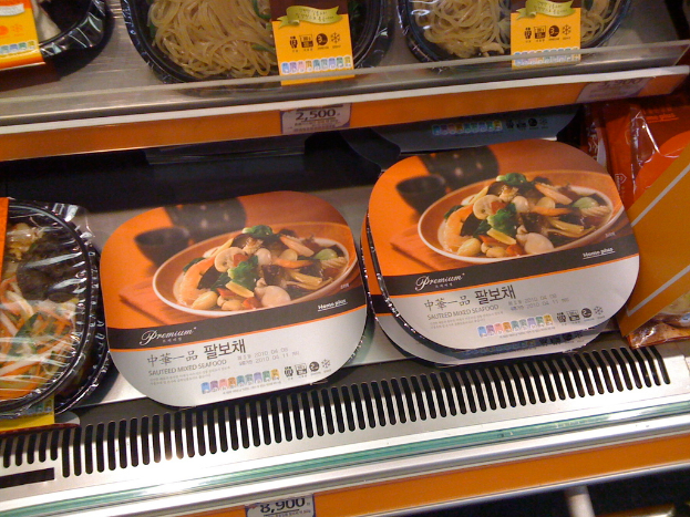 Essensboxen auf Regalen mit Preiszetteln.