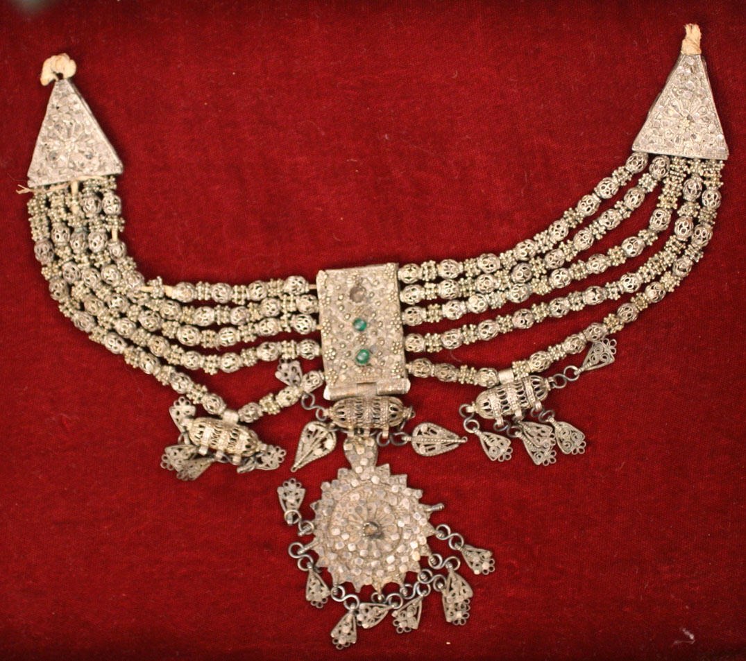 Eine Silberkette mit Smaragden und Diamanten auf rotem Samt.