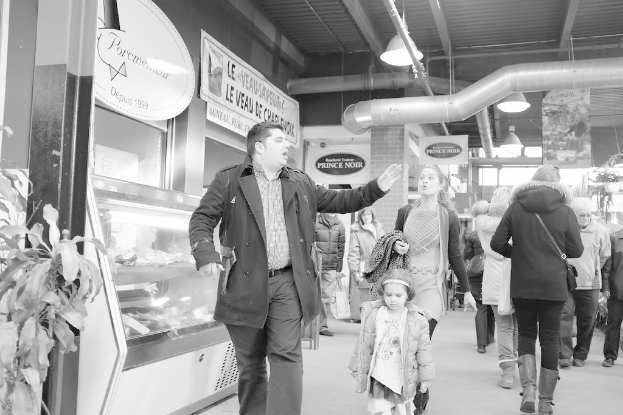 Eine Gruppe von Menschen sitzt auf dem Boden in einem Raum mit Schreibtischen, Pflanzen und Deckenleuchten.