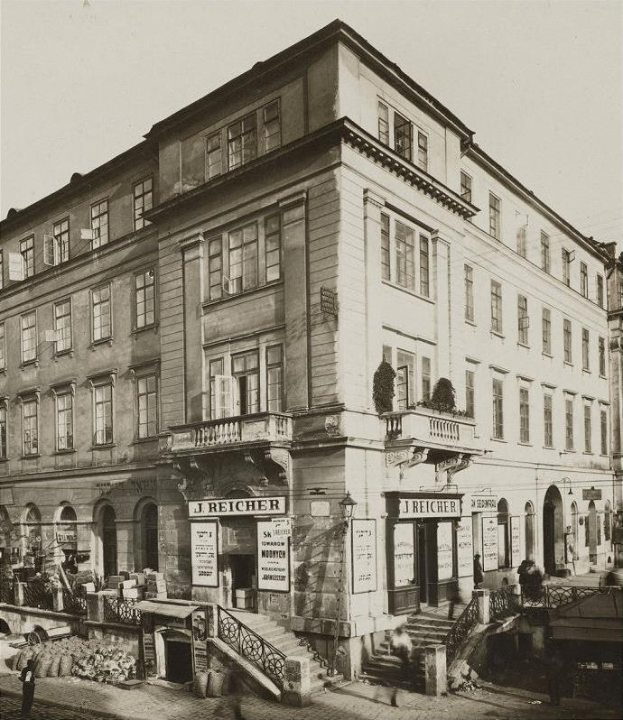 Das J Reicher Hotel in Berlin, ein altes Gebäude mit Fenstern, Treppen mit Geländern und Töpfen mit Pflanzen, mit einigen Menschen und einem sichtbaren Himmel im Hintergrund.
