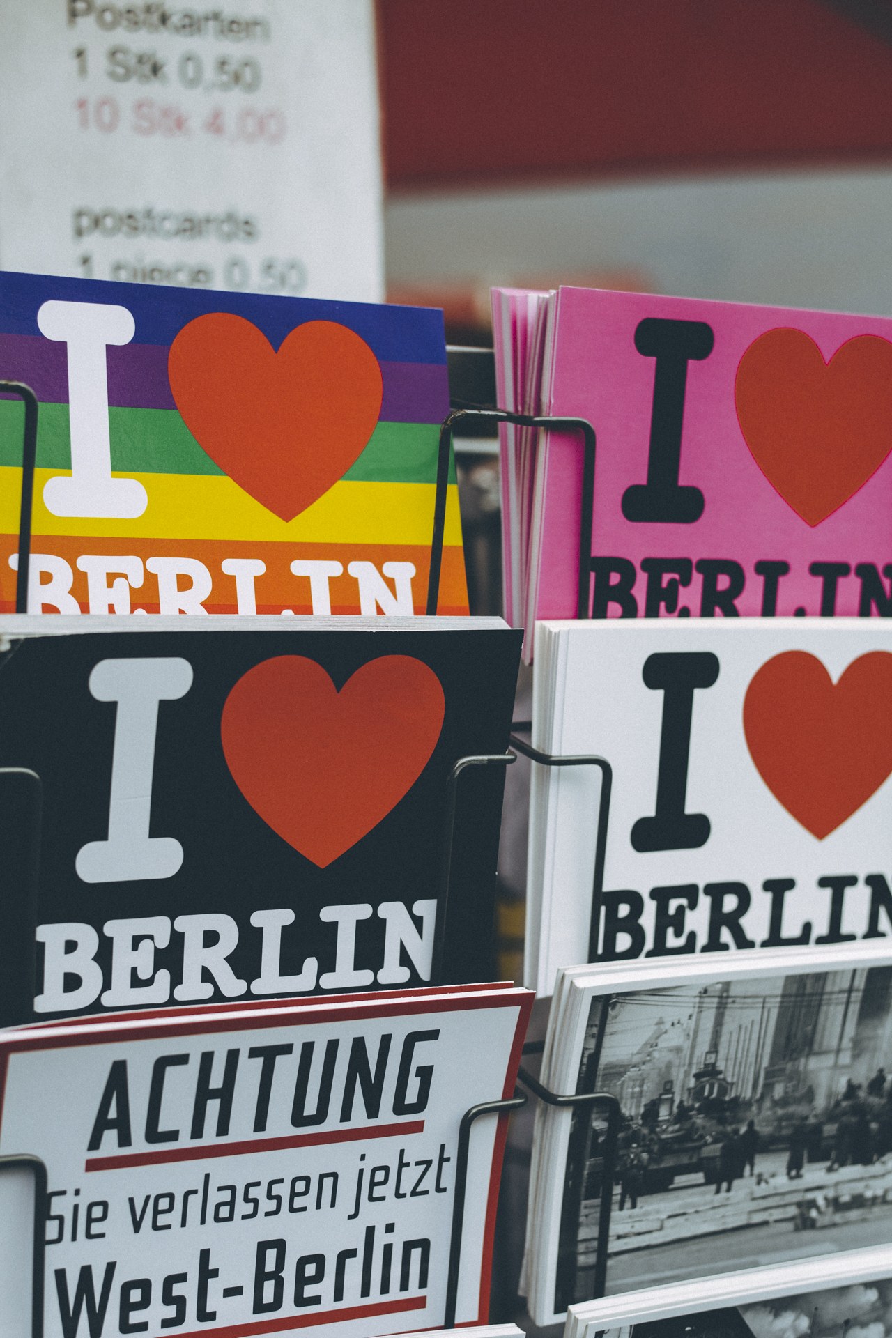 Ein Displayständer mit Büchern und Postern, auf denen der Schriftzug 'I Love Berlin' zu sehen ist, vor einem sanft unscharfen Hintergrund.