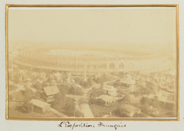 Altes Schwarz-Weiß-Foto eines Stadions in städtischer Umgebung mit umliegenden Gebäuden, Bäumen und Strommasten; unten sichtbarer Text.