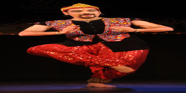 Mann in roter und schwarzer Kleidung tanzt auf der Bühne mit geschlossenen Augen und leicht geöffnetem Mund.