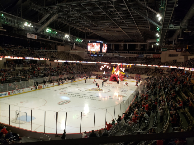 Eishockeyspiel in einer großen Arena mit Zuschauern, Eisfläche von einem Zaun umgeben, Banner, metallene Stangen und Lampen oben, zwei Bildschirme und die Columbus Blue Jackets Arena.